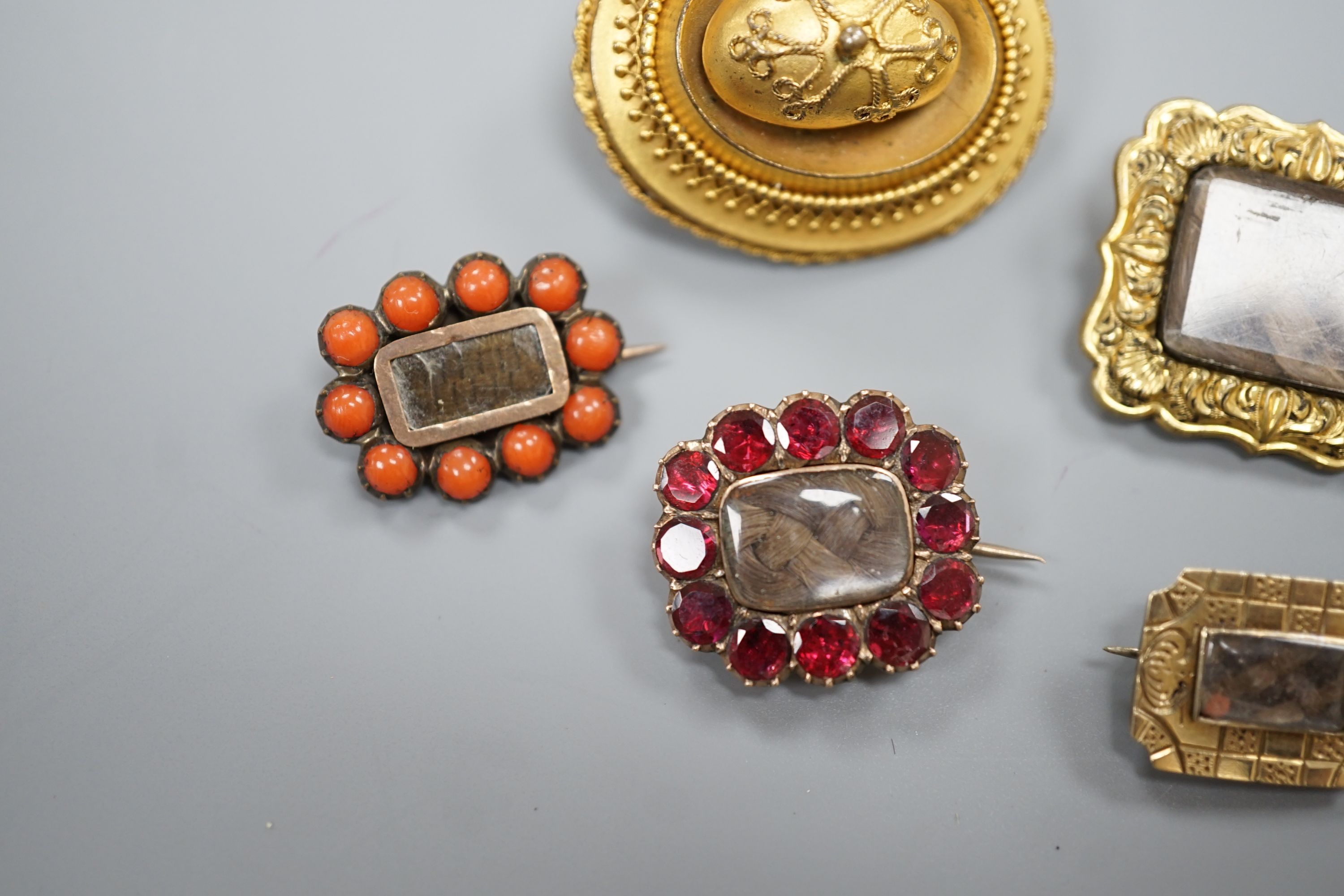 Two 19th century gilt metal and plaited hair set mourning brooches, two other mourning brooches and an oval pinchbeck brooch, largest 34mm.